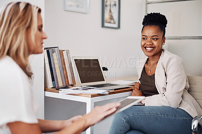 Buy stock photo Cropped shot of two attractive young businesswoman sitting together and having a discussion in the office