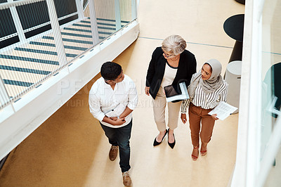 Buy stock photo High angle shot of a group of businesspeople walking alongside each other in an office