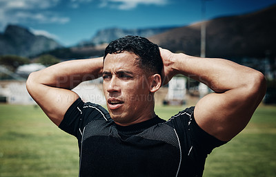 Buy stock photo Cropped shot of a handsome young rugby player standing with his hands behind his head in a rugby field