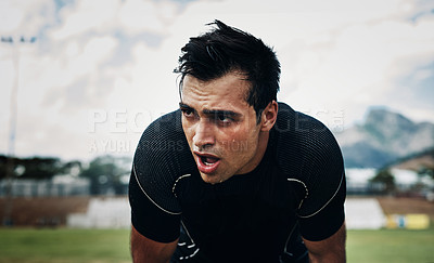 Buy stock photo Cropped shot of a handsome young rugby player taking a break on the field during the day