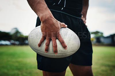Buy stock photo Cropped shot of an unrecognizable rugby player holding a rugby ball on the field during the day
