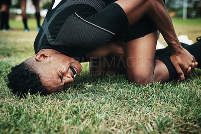 Buy stock photo Cropped shot of a handsome young rugby player suffering with an injury on the field