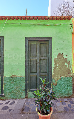 Buy stock photo Old abandoned house or home with a weathered green wall and aging wooden door. Vintage and aged residential building built in a traditional architectural style or design with a cobble stone road