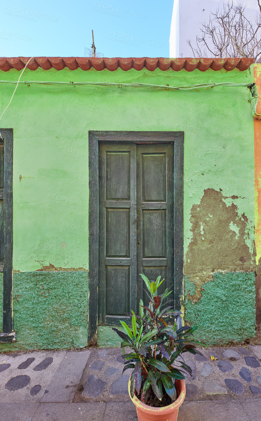 Buy stock photo Old abandoned house or home with a weathered green wall and aging wooden door. Vintage and aged residential building built in a traditional architectural style or design with a cobble stone road