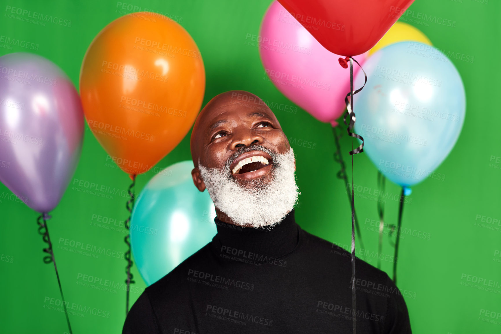 Buy stock photo Studio shot of a man posing against a green background with balloons around him