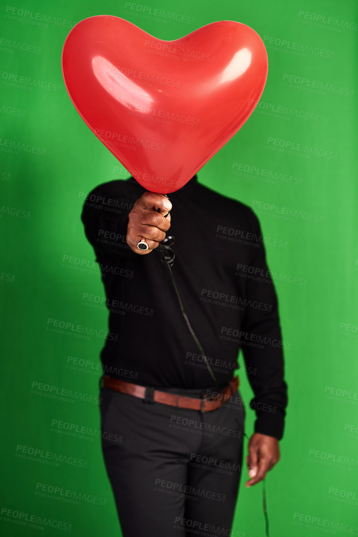 Buy stock photo Cropped shot of a man posing with a heart-shaped balloon in front of his face