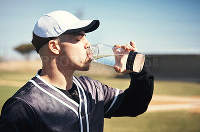 Buy stock photo Shot of a young man drinking water after playing a game of baseball