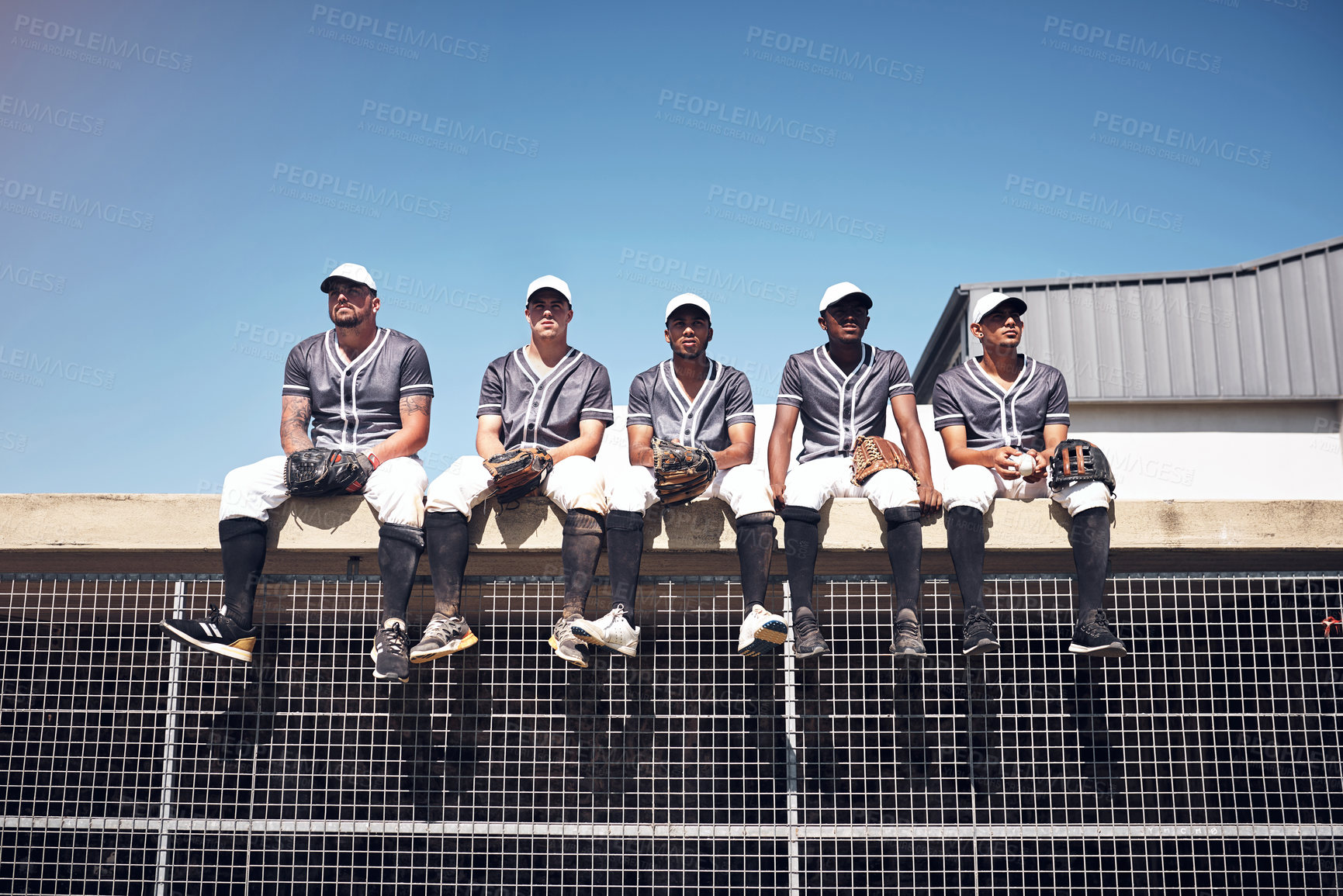 Buy stock photo Shot of a group of young men sitting on top of the dugout and watching a baseball game