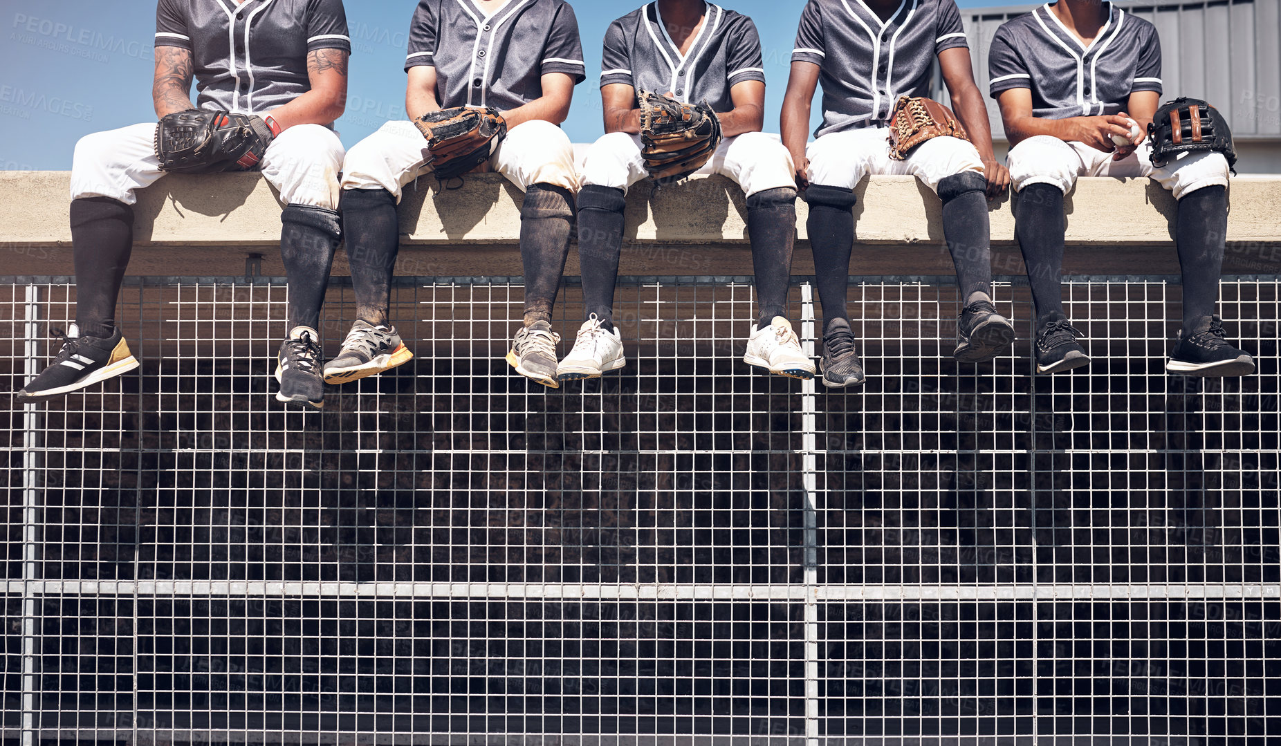 Buy stock photo Cropped shot of a group of men sitting on top of the dugout and watching a baseball game