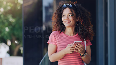 Buy stock photo Cropped shot of a young woman using her cellphone while walking through the city