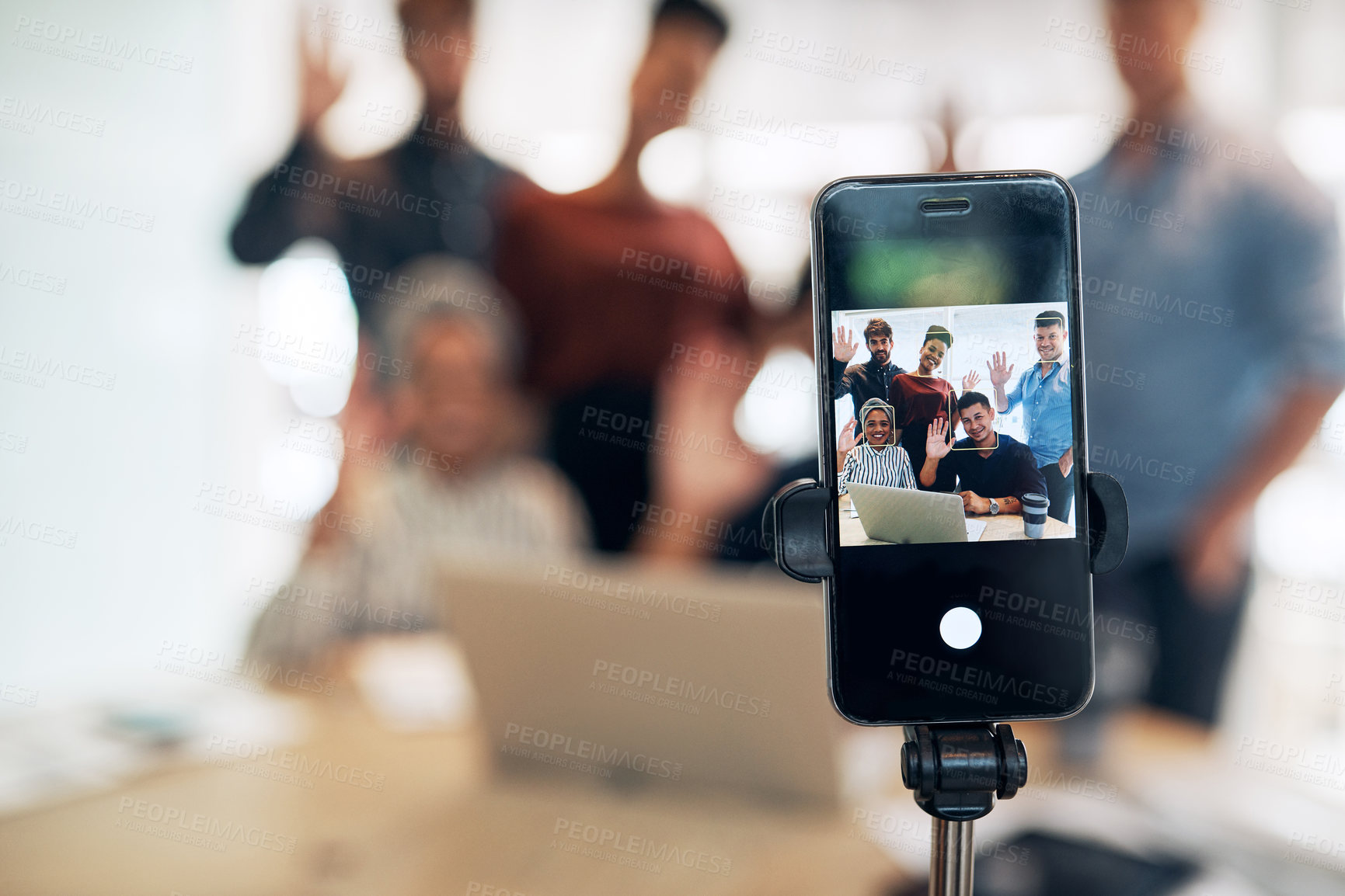 Buy stock photo Shot of a group of businesspeople waving while making a conference call on a cellphone in an office