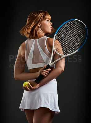 Buy stock photo Cropped shot of a woman posing with a tennis racket and ball against a dark background