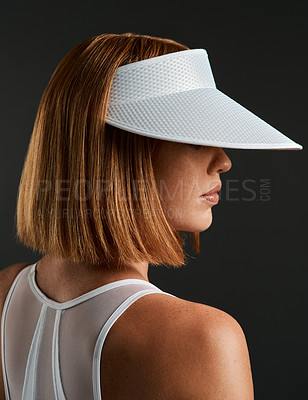 Buy stock photo Cropped shot of a sporty young woman wearing a sun visor against a dark background