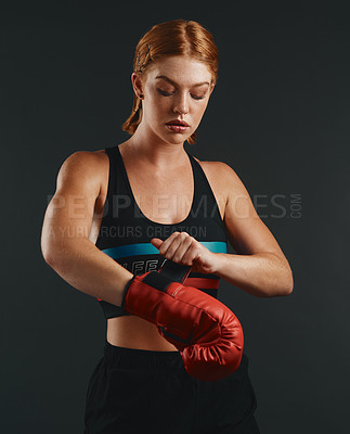 Buy stock photo Studio shot of a sporty young woman wearing boxing gloves against a black background