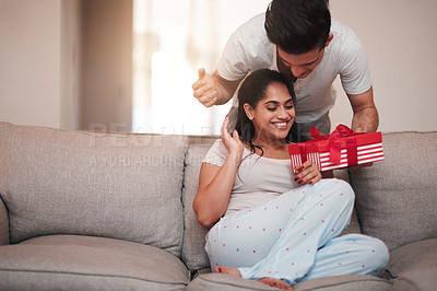 Buy stock photo Gift, smile and surprise with interracial couple on sofa in living room of home together for romance. Box, present or wow with man and woman in apartment for birthday or valentines day celebration