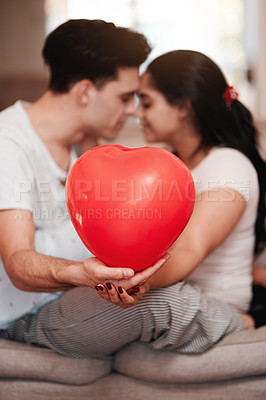 Buy stock photo Balloon, heart and love with interracial couple on sofa in living room of home together for romance. Emoji, shape or valentines day with man and woman in apartment for bonding, commitment or support