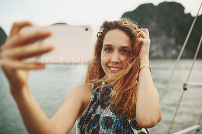 Buy stock photo Shot of a young woman taking selfies on a boat ride in Vietnam with her smartphone