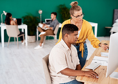 Buy stock photo Shot of two young designers working together on a computer in an office