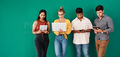 Buy stock photo Shot of a group of young designers using digital devices while standing together against a green background
