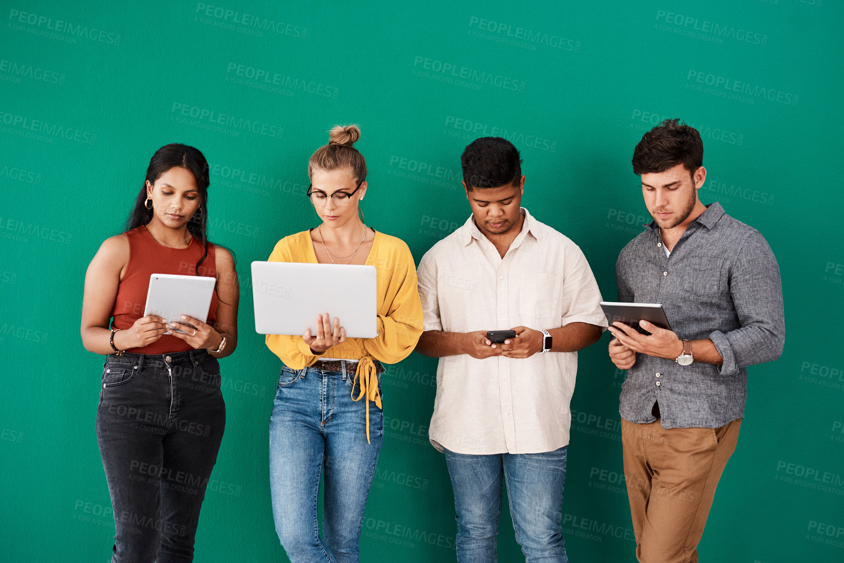 Buy stock photo Creative people, waiting room and row with technology for career search or job opportunity on a green studio background. Young, group or interns with laptop, tablet or phone in line for interview