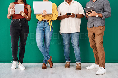 Buy stock photo Closeup shot of a group of unrecognisable designers using digital devices while standing together against a green background