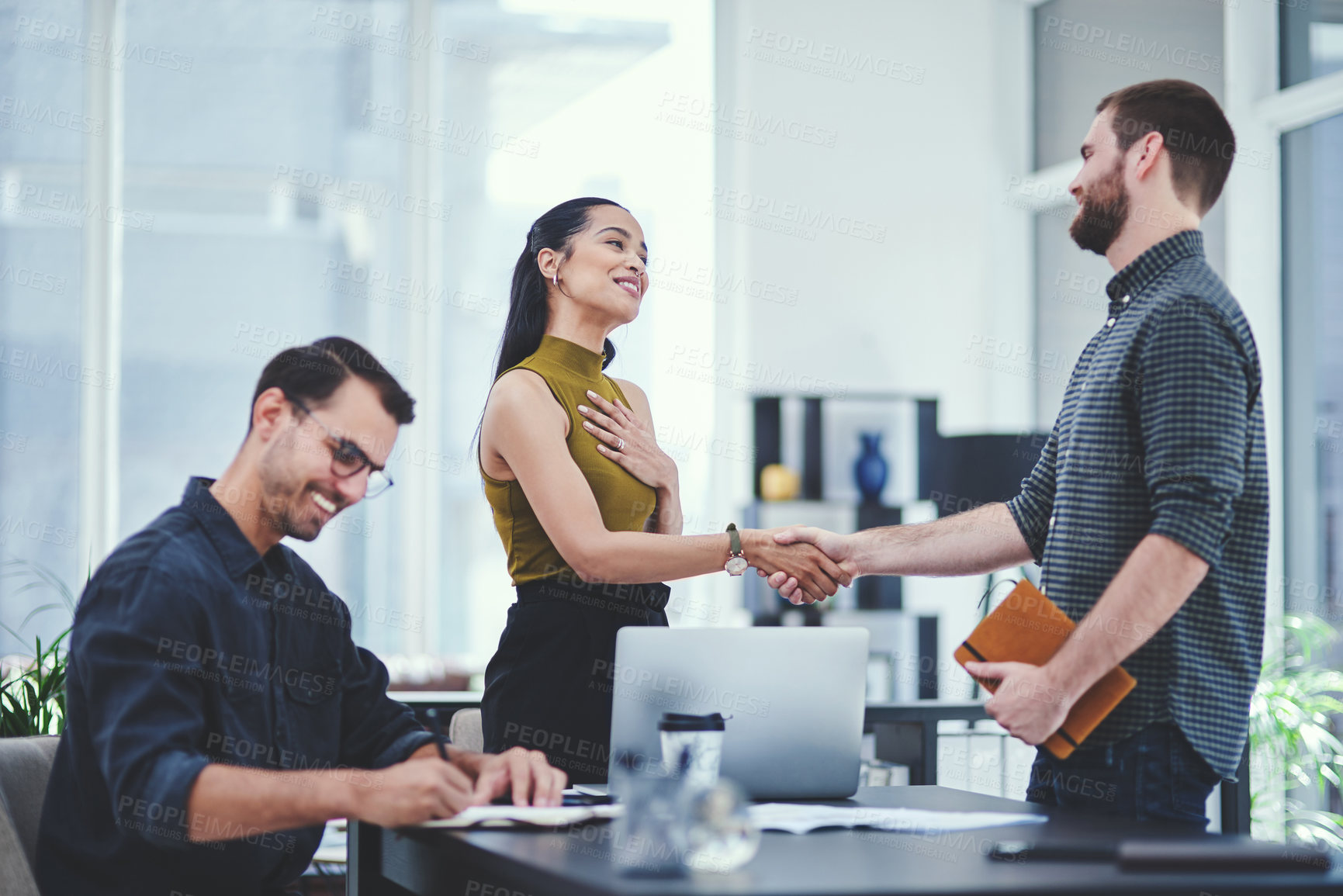 Buy stock photo Handshake, thank you and smile in office, people and meeting for project, paperwork or celebration. Colleagues, holding hands and creative for journalism, laptop and proud of collaboration or article