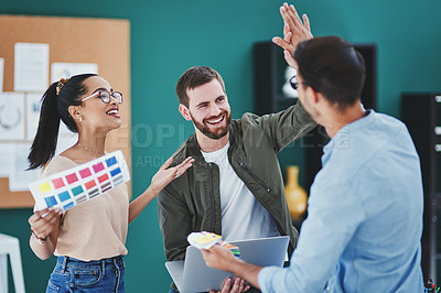 Buy stock photo Shot of two young designers giving each other a high five while having a discussion in an office