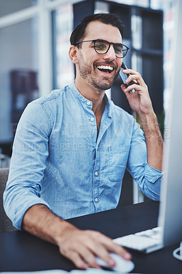 Buy stock photo Shot of a young designer talking on a cellphone while working on a computer in an office