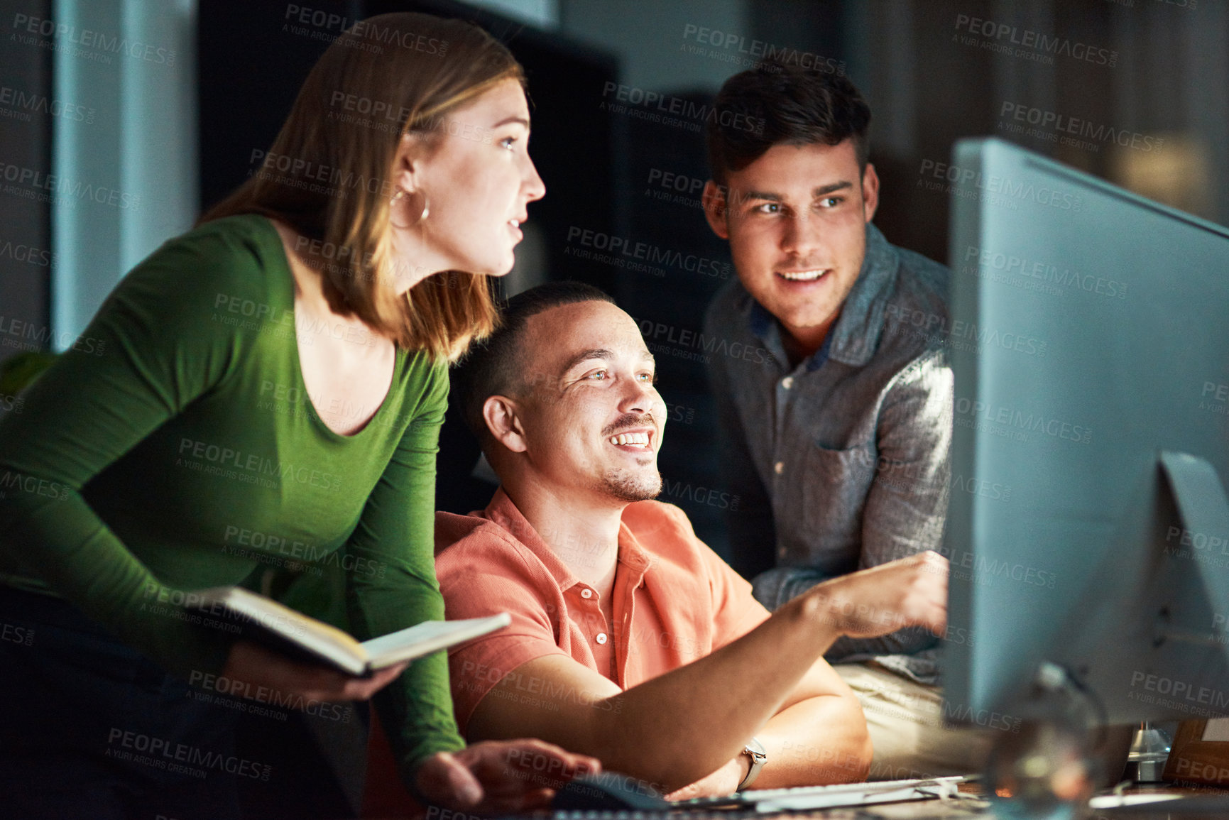 Buy stock photo Shot of a group of designers looking at something on a computer while working late