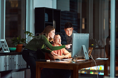 Buy stock photo Shot of a group of designers looking at something on a computer while working late