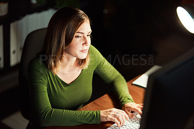 Buy stock photo Cropped shot of a young woman using her computer while working late