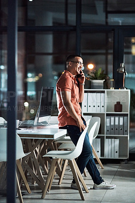 Buy stock photo Shot of a businessman talking on his cellphone while working late at the office