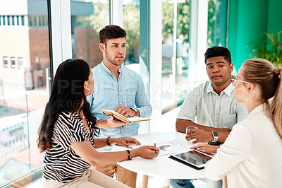Buy stock photo Cropped shot of a group of young business colleagues gathered around a table in their office