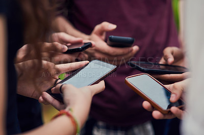 Buy stock photo Closeup of a group of young unrecognizable people standing in a circle while browsing on their mobile phones outside during the day