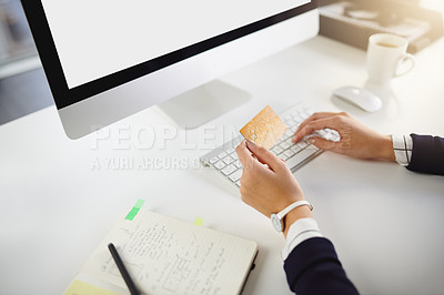 Buy stock photo Shot of an unrecognizable young businesswoman holding a bank card and using her computer in a modern office