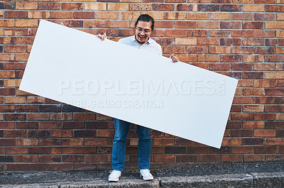 Buy stock photo Shot of a young man holding a blank banner against an urban background outdoors
