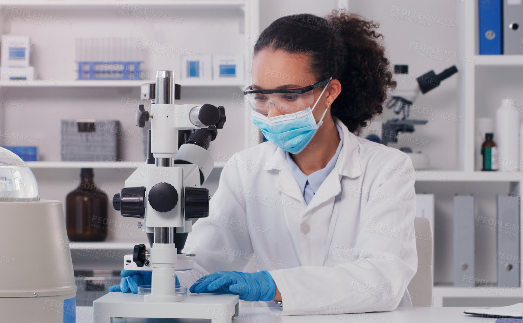 Buy stock photo Shot of a young scientist using a microscope in a lab