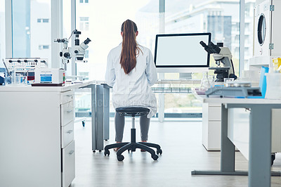 Buy stock photo Rearview shot of a focused young female scientist conducting experiments inside of a laboratory during the day
