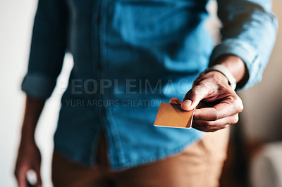 Buy stock photo Cropped shot of an unrecognizable businessman standing alone in his home office and holding out a credit card