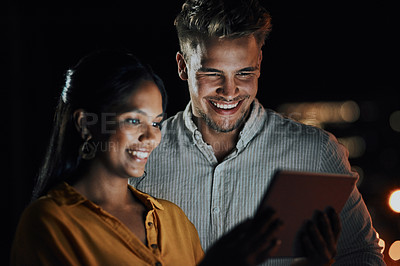 Buy stock photo Shot of two businesspeople using a digital tablet together outside an office at night