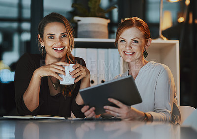 Buy stock photo Portrait of two businesswomen using a digital tablet together in an office at night