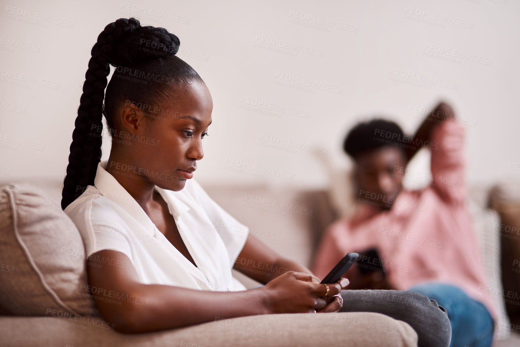 Buy stock photo Defocused of a woman using her cellphone while her partner sits in the background