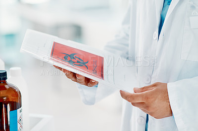 Buy stock photo Shot of a scientist holding a folder with a hazardous symbol on it in a laboratory