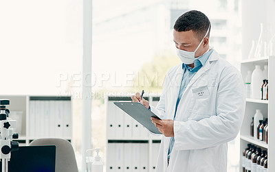 Buy stock photo Shot of a young scientist writing notes on a clipboard in a laboratory