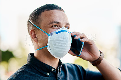 Buy stock photo Shot of a young businessman wearing a mask and using a smartphone against a city background