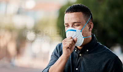 Buy stock photo Shot of a young man coughing and wearing a mask against a city background