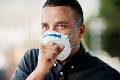 Buy stock photo Shot of a young man coughing and wearing a mask against a city background