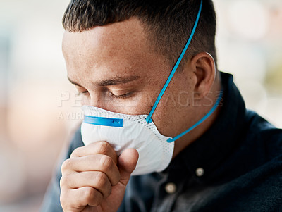 Buy stock photo Shot of a young man coughing and wearing a mask against a city background