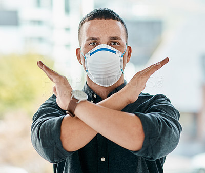 Buy stock photo Portrait of a young businessman wearing a mask and crossing his arms in a modern office