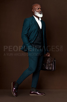 Buy stock photo Studio shot of a well-dressed businessman carrying his briefcase against a brown background